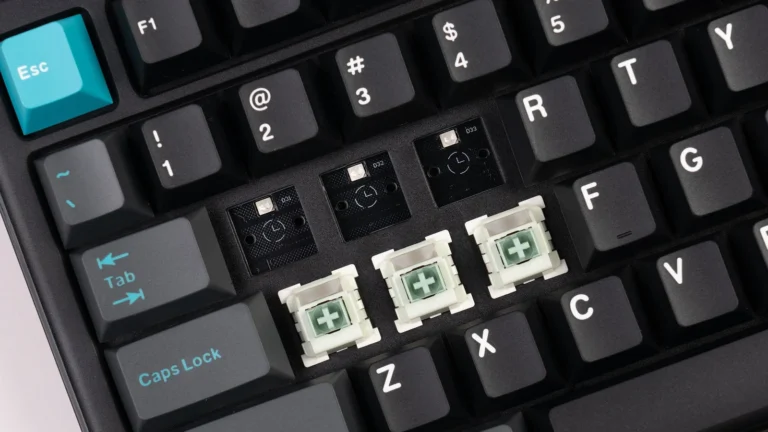 Prim-plan cu trei switch-uri magnetice Keychron Lime scoase din tastatură și soclurile hot-swap rămase libere pe placă