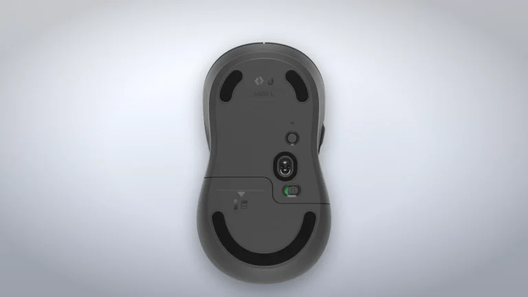 Partea de dedesubt a mouse-ului Logitech Signature M650 L, cu senzorul optic, comutatorul de pornire și capacul compartimentului din spate